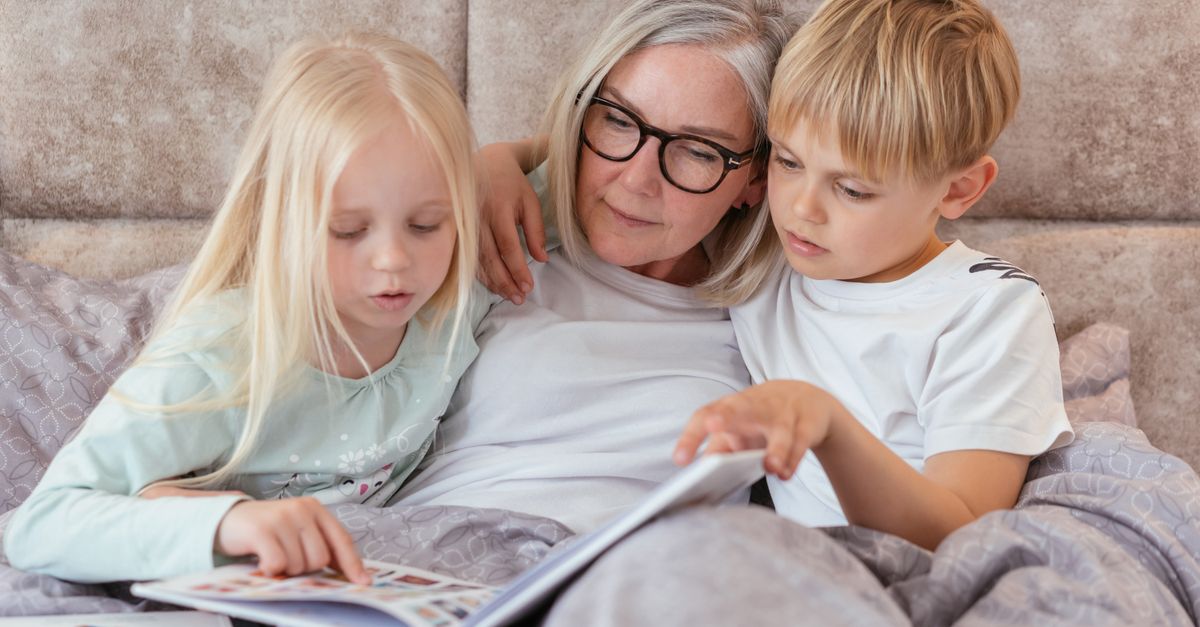 A grandmother reading stories with her two grandchildren on a cozy couch